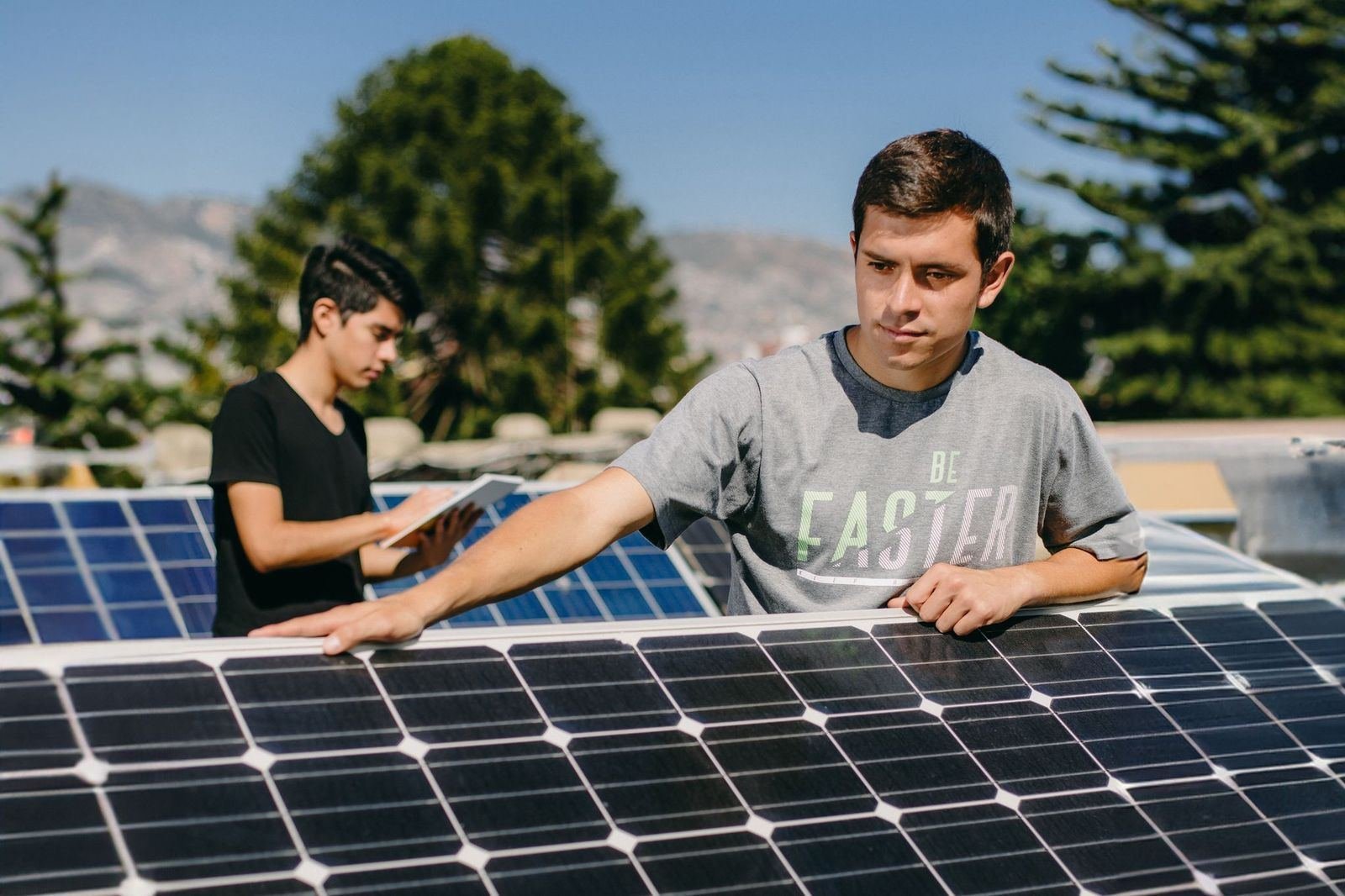 Two students installing solar panels for an AC3E project