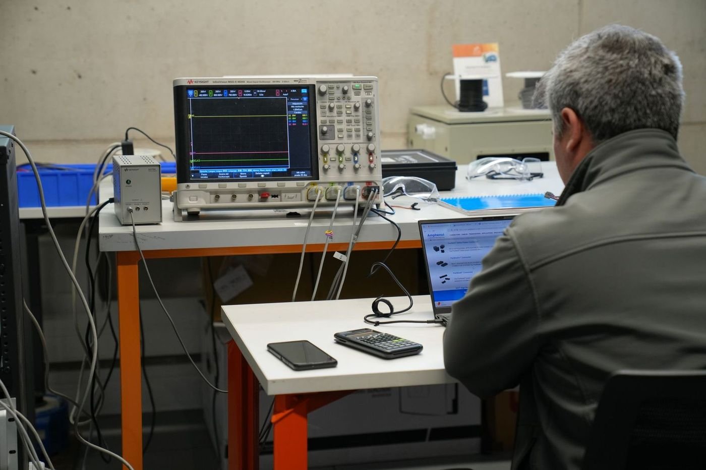 Researcher working with electronic instrumentation at an AC3E test bench